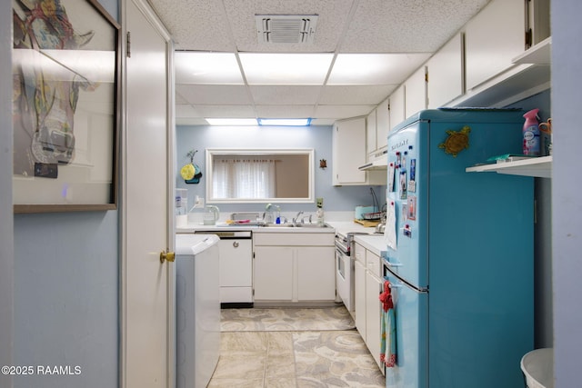 kitchen with high end range, white cabinetry, sink, refrigerator, and a drop ceiling