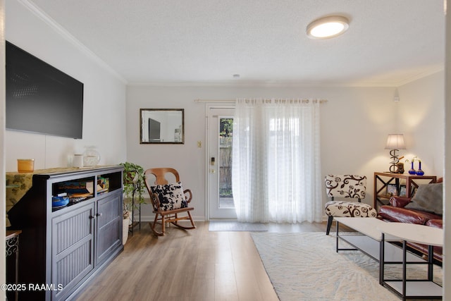 living room with a textured ceiling, ornamental molding, and light hardwood / wood-style floors