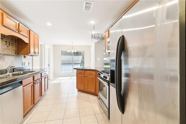 kitchen with tasteful backsplash, dark countertops, stainless steel appliances, a sink, and light tile patterned flooring