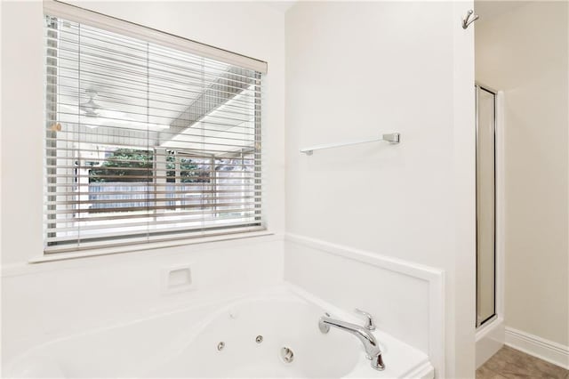 bathroom featuring a jetted tub and a shower stall