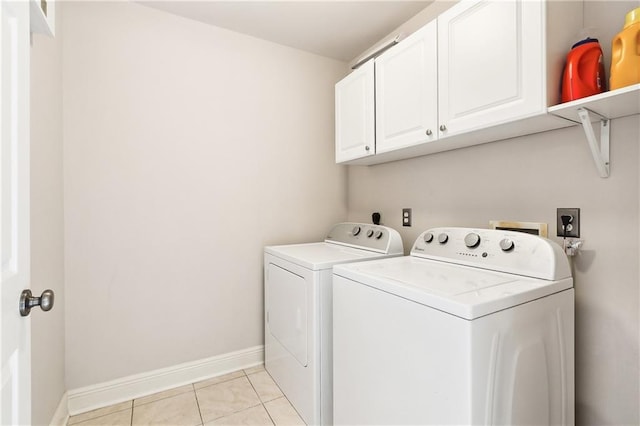 clothes washing area with light tile patterned floors, washer and clothes dryer, cabinet space, and baseboards