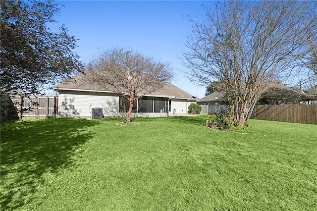 rear view of house with a sunroom, a fenced backyard, cooling unit, and a yard