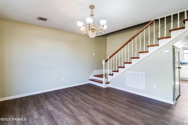 stairs with hardwood / wood-style flooring, a textured ceiling, and an inviting chandelier