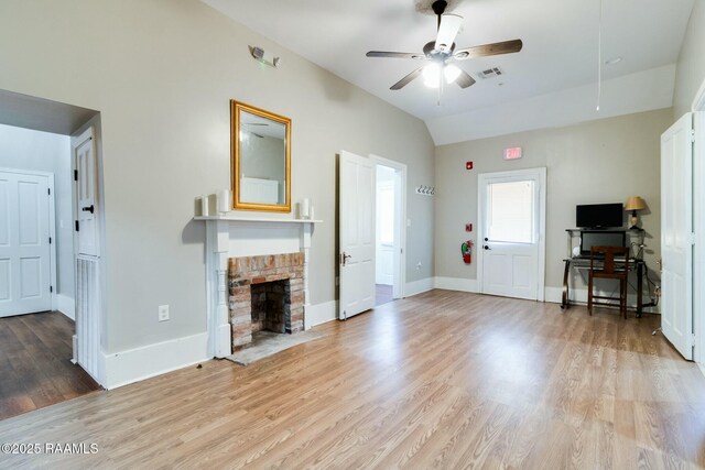 unfurnished living room with vaulted ceiling, ceiling fan, light hardwood / wood-style floors, and a brick fireplace