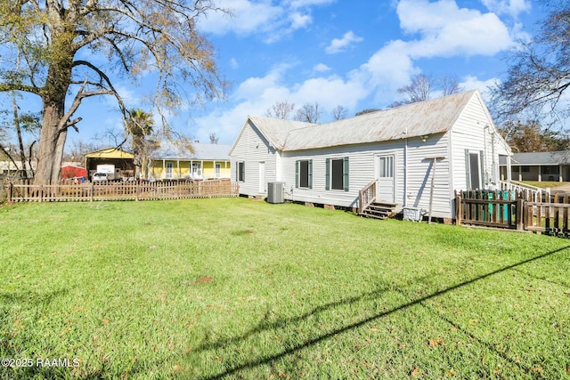 rear view of house with central AC and a yard