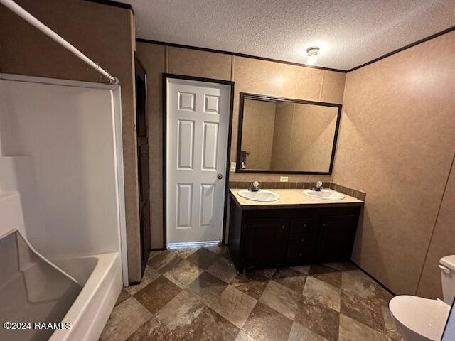 full bathroom featuring a textured ceiling, shower / tub combination, vanity, and toilet