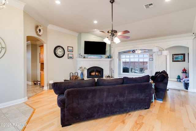 living room featuring vaulted ceiling, ornamental molding, ceiling fan, a fireplace, and light hardwood / wood-style floors