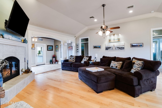 living room featuring hardwood / wood-style flooring, ornamental molding, lofted ceiling, and a fireplace