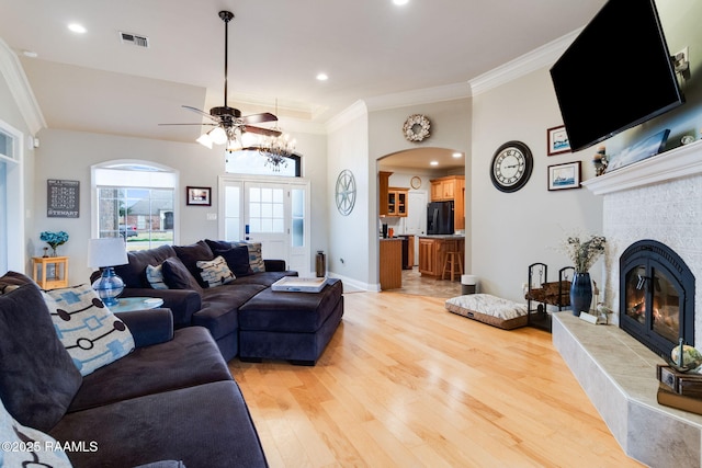 living room with crown molding, a fireplace, and light hardwood / wood-style flooring