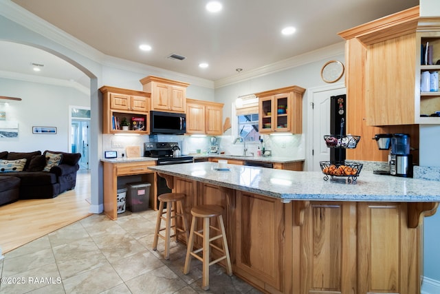 kitchen with light stone counters, black appliances, a kitchen breakfast bar, and kitchen peninsula