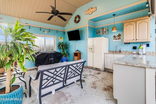 kitchen featuring vaulted ceiling, decorative light fixtures, white fridge with ice dispenser, ceiling fan, and light stone countertops