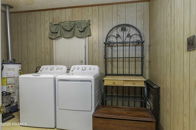 clothes washing area featuring water heater, separate washer and dryer, and wood walls