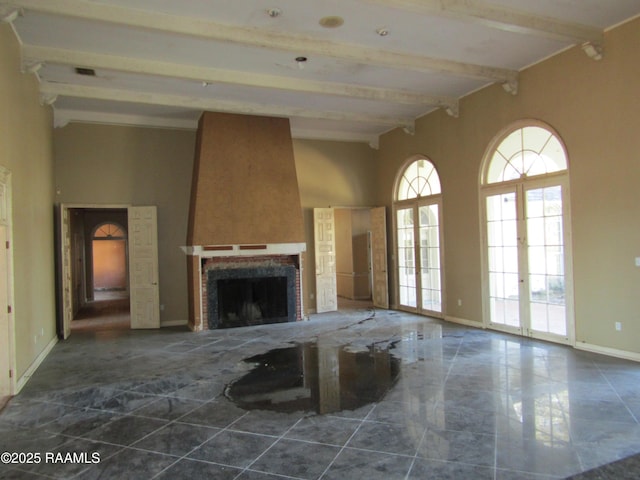 unfurnished living room with french doors, a large fireplace, and beamed ceiling