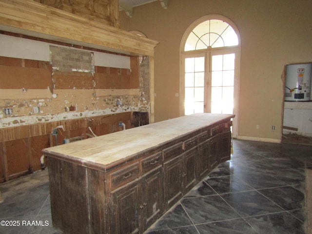 kitchen with dark tile patterned flooring, french doors, gas water heater, a kitchen island, and dark brown cabinetry