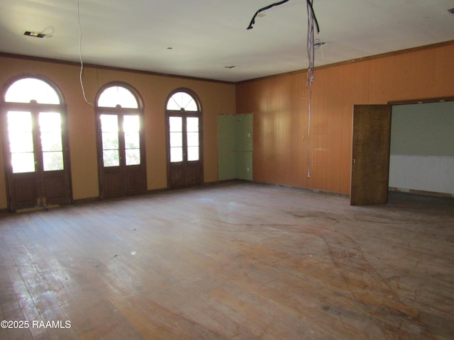 unfurnished room with ornamental molding, wood walls, and french doors