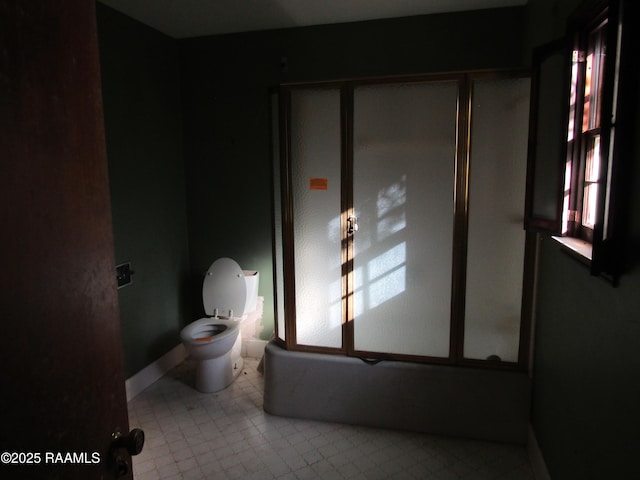 bathroom featuring toilet, enclosed tub / shower combo, and tile patterned flooring