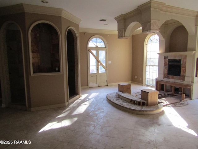 unfurnished living room featuring a wealth of natural light and ornamental molding