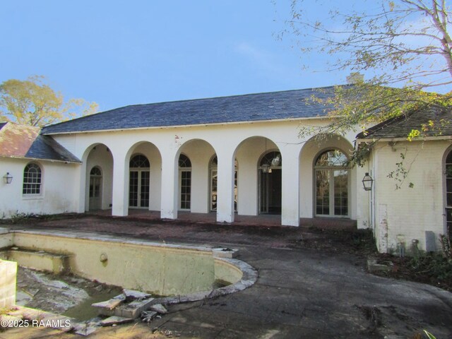 exterior space featuring a shingled roof and stucco siding