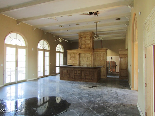 unfurnished living room featuring a ceiling fan, beamed ceiling, and a high ceiling