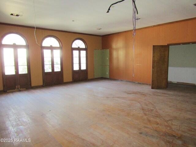 spare room featuring crown molding, light wood-style flooring, and wooden walls