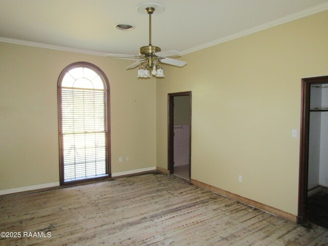 spare room with ceiling fan, visible vents, crown molding, baseboards, and light wood finished floors