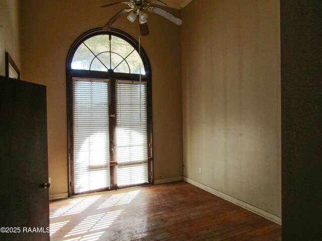 unfurnished room featuring a healthy amount of sunlight, baseboards, a ceiling fan, and hardwood / wood-style floors