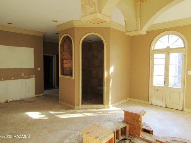 spare room with crown molding and arched walkways