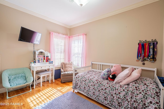 bedroom with ornamental molding and wood finished floors