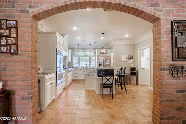 kitchen featuring appliances with stainless steel finishes, a breakfast bar, a center island, hanging light fixtures, and crown molding