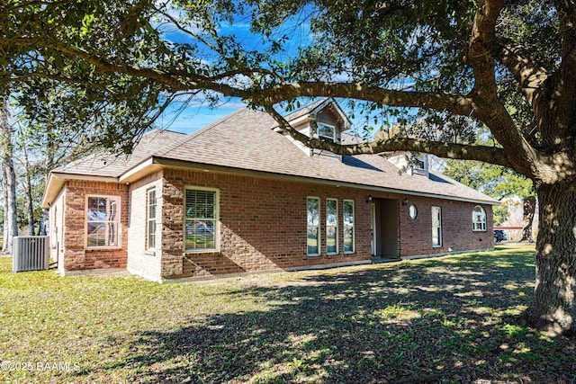 rear view of house with a yard, brick siding, and a shingled roof