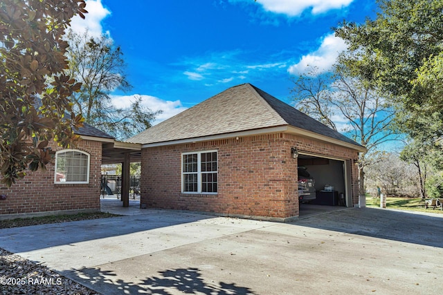 view of property exterior featuring a garage, concrete driveway, brick siding, and roof with shingles