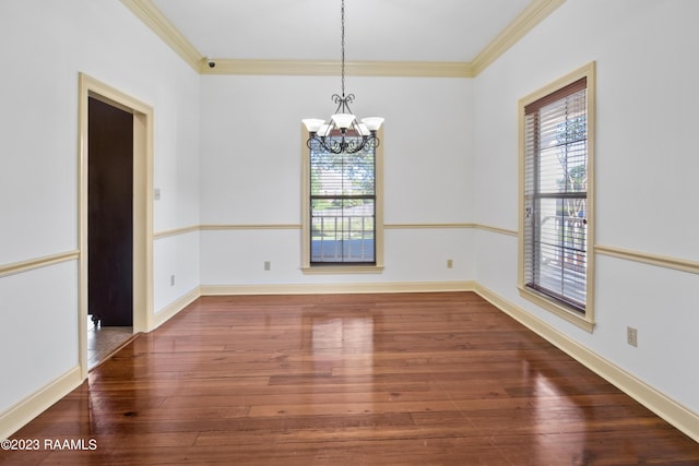 empty room featuring ornamental molding, a chandelier, and hardwood / wood-style floors