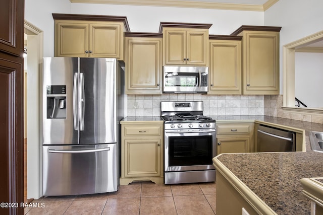 kitchen with decorative backsplash, stainless steel appliances, ornamental molding, light tile patterned floors, and cream cabinetry