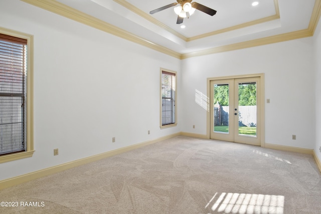 unfurnished room with light carpet, french doors, ornamental molding, a raised ceiling, and ceiling fan