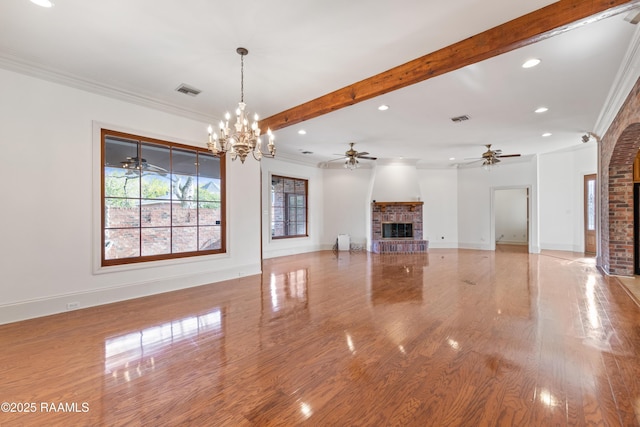 unfurnished living room with beamed ceiling, ornamental molding, and a healthy amount of sunlight