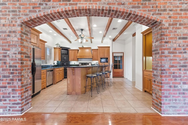 kitchen featuring a breakfast bar, a kitchen island, stainless steel appliances, light tile patterned flooring, and custom exhaust hood