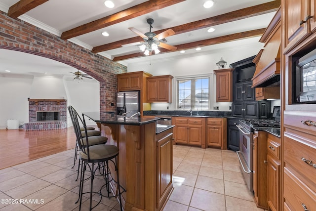 kitchen with a kitchen bar, light tile patterned flooring, an island with sink, and appliances with stainless steel finishes