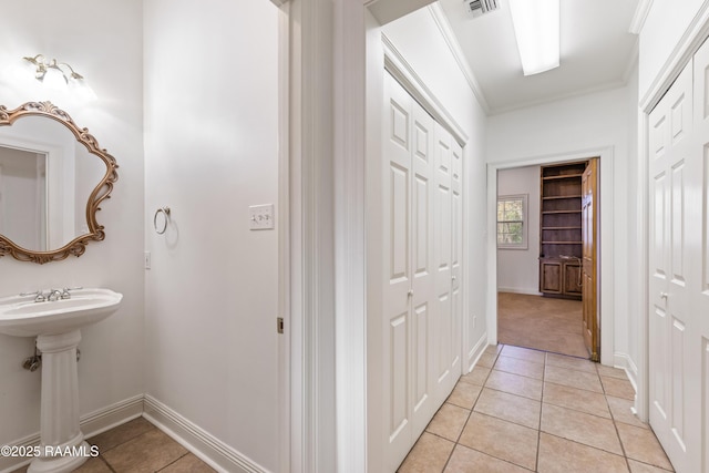 hallway with crown molding, sink, and light tile patterned floors