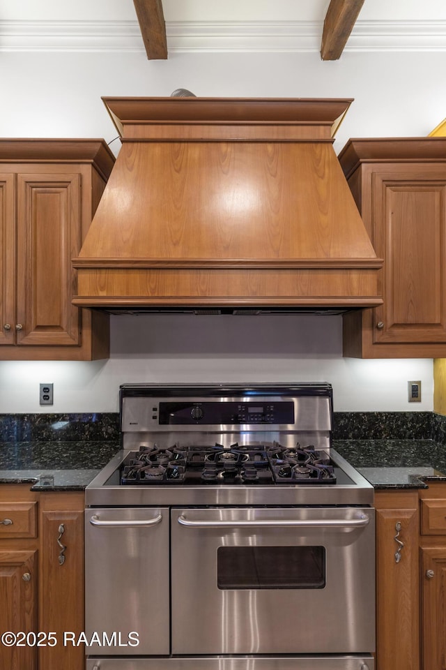 kitchen with range with two ovens, ornamental molding, dark stone countertops, and beamed ceiling