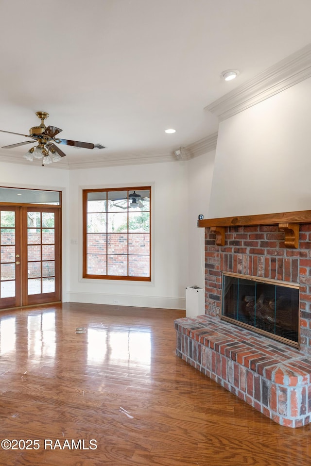 unfurnished living room featuring a fireplace, wood-type flooring, ornamental molding, ceiling fan, and french doors