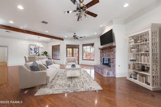 living room featuring a brick fireplace, ornamental molding, dark hardwood / wood-style flooring, beam ceiling, and ceiling fan with notable chandelier