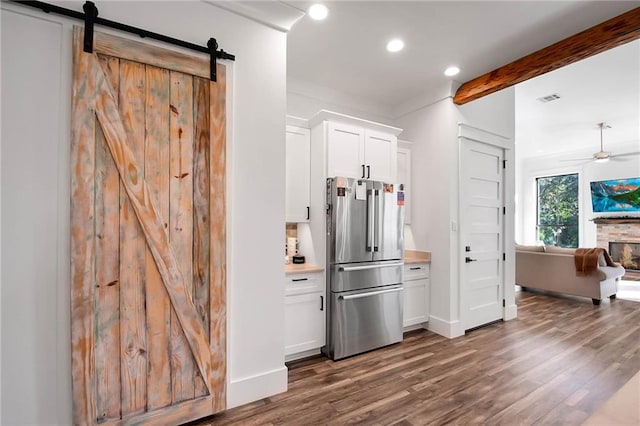 kitchen featuring dark wood-type flooring, freestanding refrigerator, visible vents, and a barn door