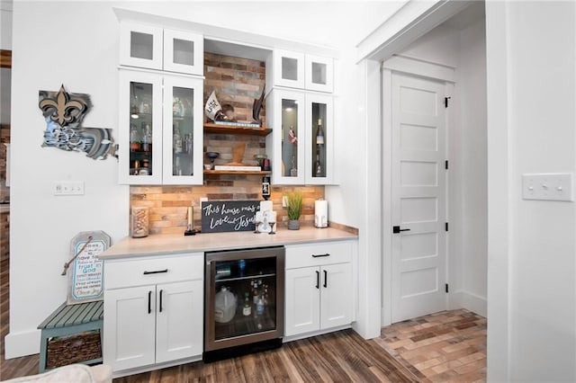 bar with a bar, beverage cooler, decorative backsplash, and wood finished floors