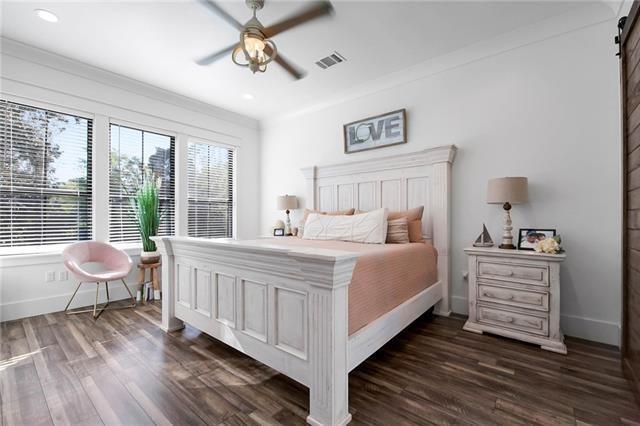 bedroom with a barn door, visible vents, baseboards, dark wood finished floors, and crown molding