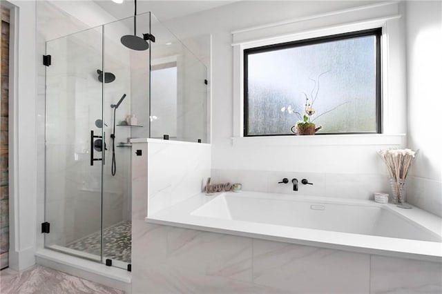 bathroom featuring a stall shower, a healthy amount of sunlight, and a garden tub