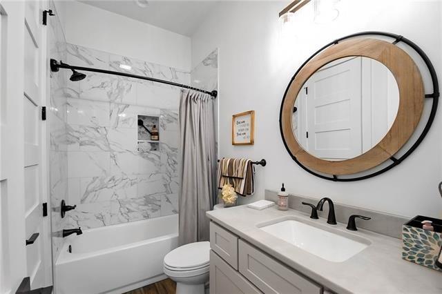 bathroom with vanity, shower / bath combo with shower curtain, and toilet