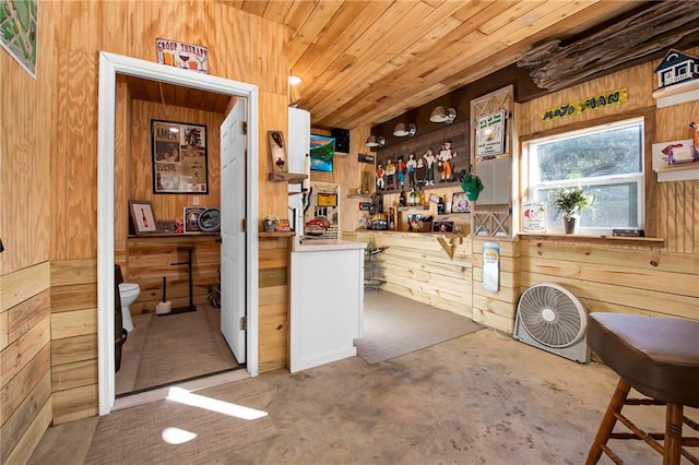 interior space with concrete flooring, open shelves, wood walls, and wooden ceiling