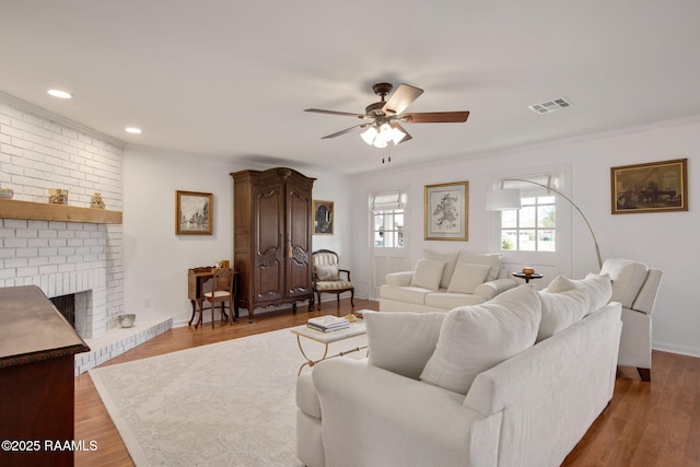 living room with ceiling fan, dark hardwood / wood-style flooring, crown molding, and a fireplace