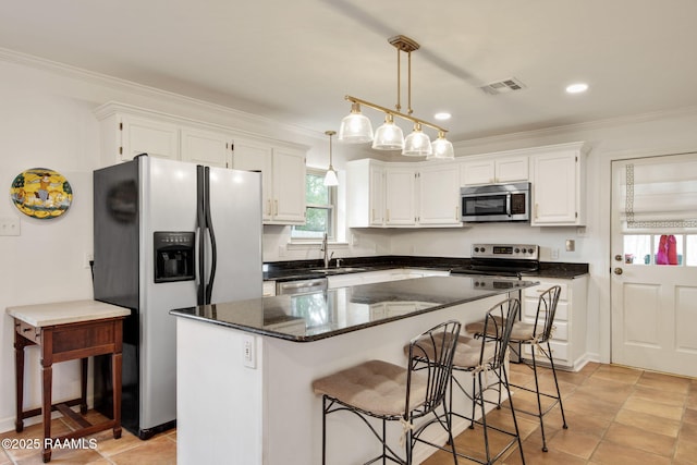 kitchen featuring stainless steel appliances, white cabinetry, hanging light fixtures, and a center island