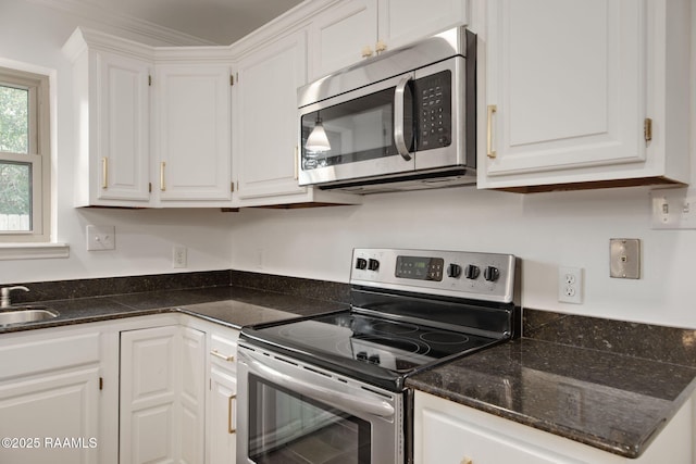 kitchen featuring sink, crown molding, white cabinetry, appliances with stainless steel finishes, and dark stone counters